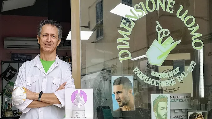 Vincenzo Leone davanti alla vetrina con immagini di tagli da uomo